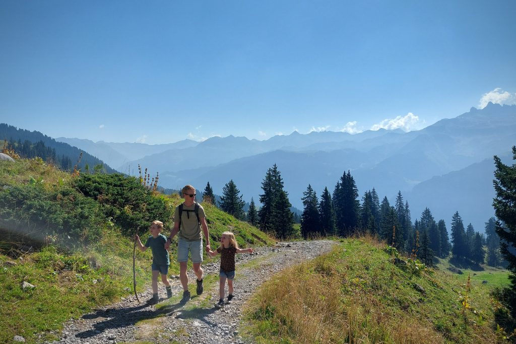 Vader met twee jonge kinderen wandelt met een prachtig uitzicht door de Zwitserse bergen op een prachtige zomerdag.