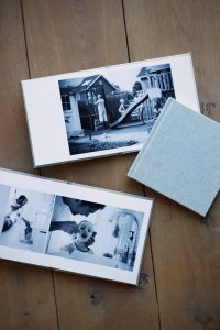 productfoto in kleur van de fotoalbums die inbegrepen zijn bij gewoon-een-dag-shoots van ellenklikt. Drie albums zijn te zien, waarvan er twee opengeslagen liggen op een pagina met zwart-witfoto's.